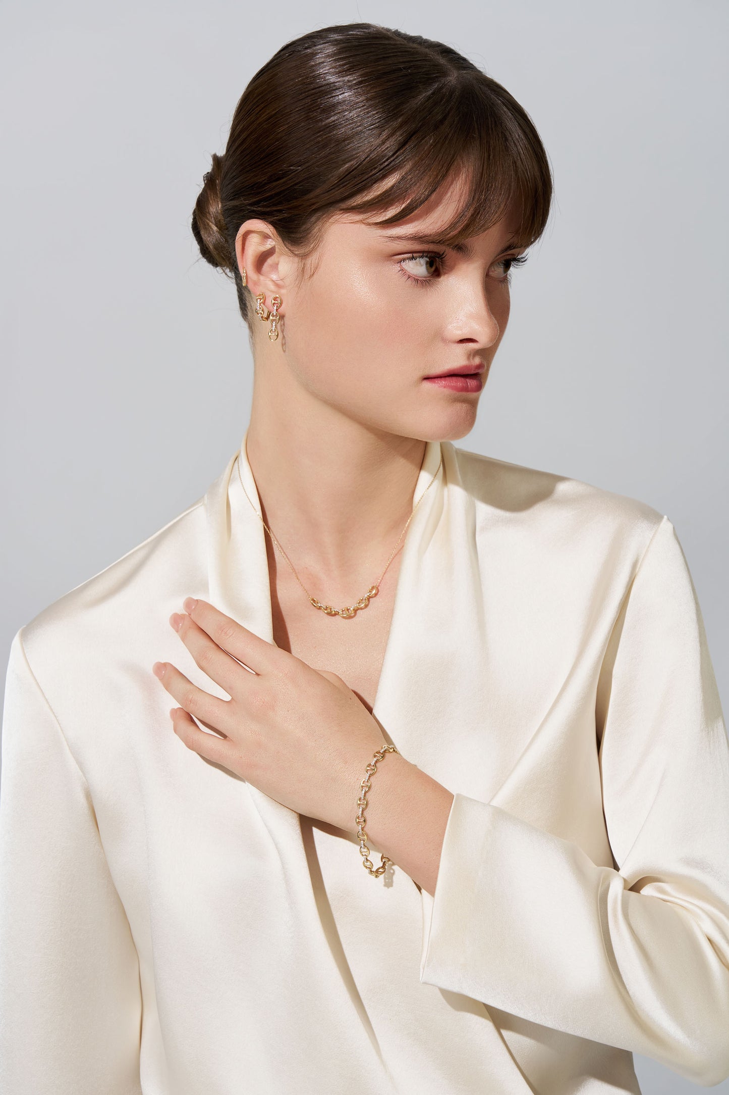 Woman wearing gold jewellery in white background.