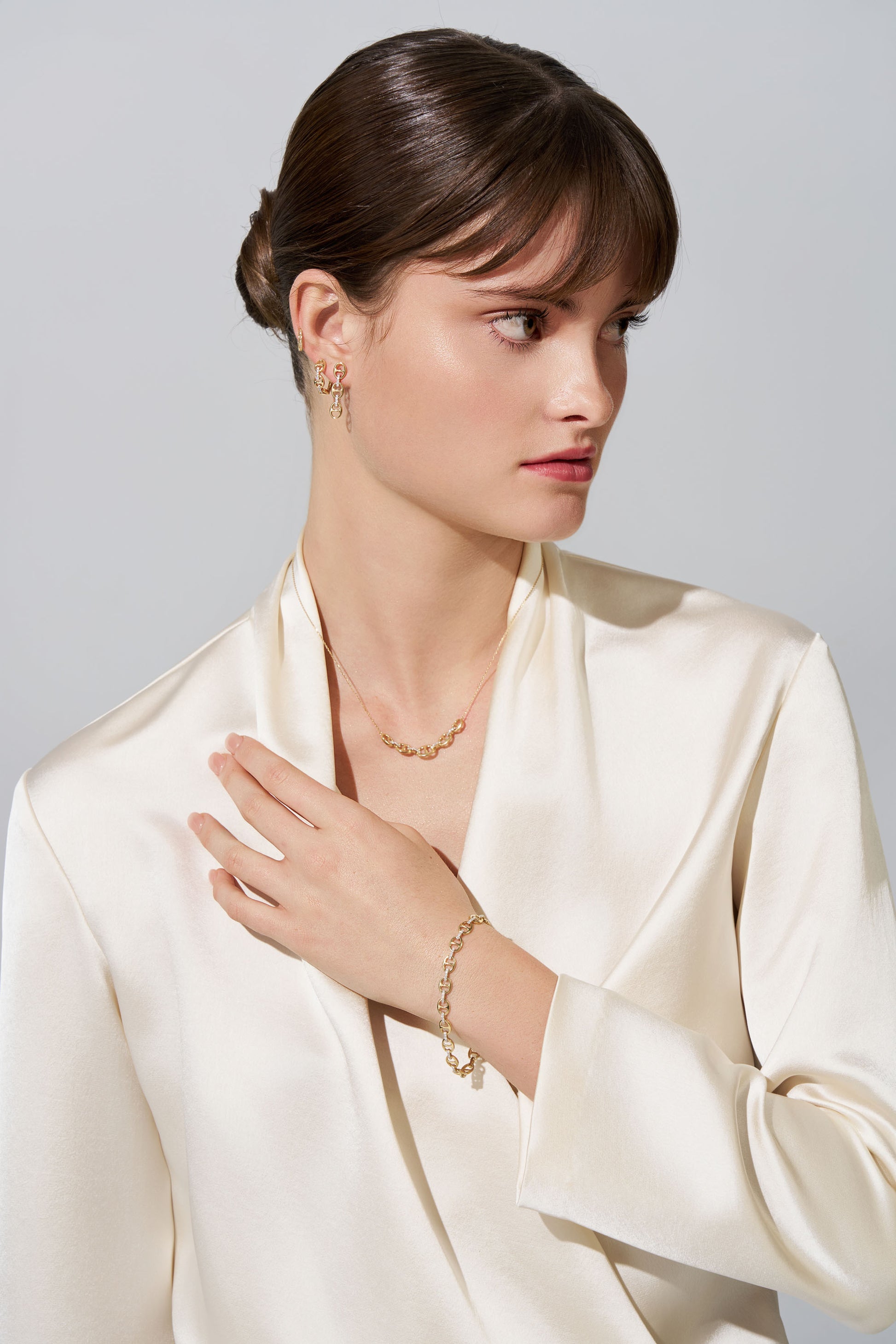 Woman wearing gold jewellery in white background.
