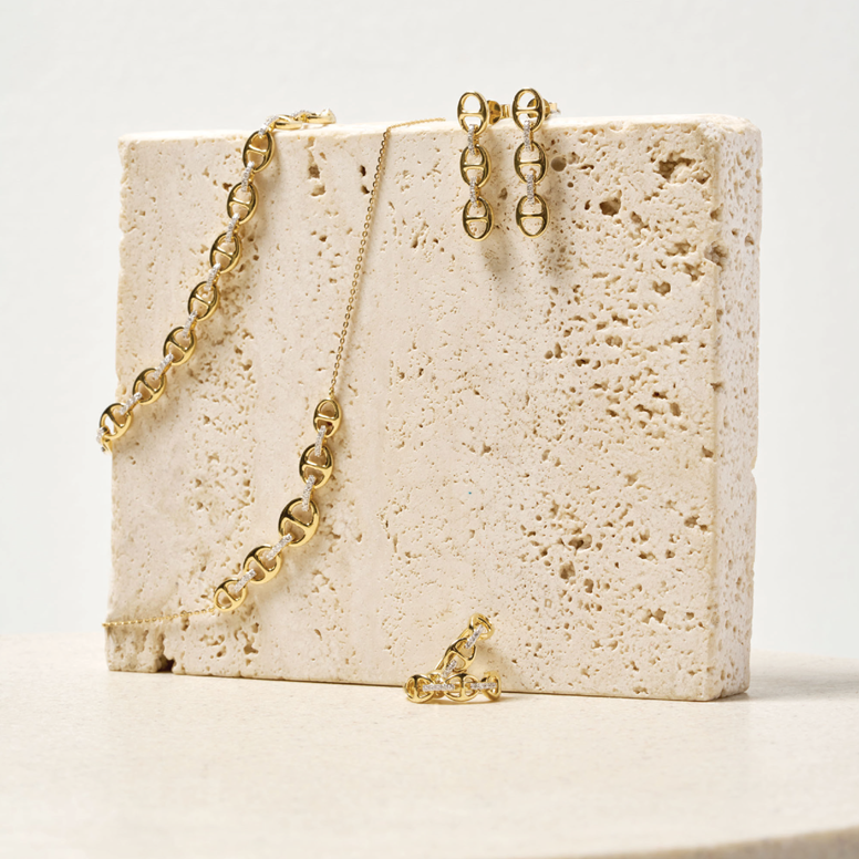 Gold necklace and earrings on a textured stone surface